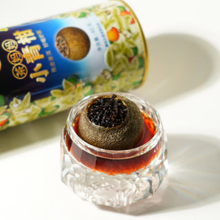 Orange tea in a glass container with a tea canister in the background